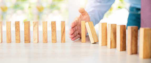 Close-up hand prevent wooden block not falling domino concepts of financial risk management and...