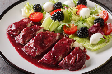 Tender chicken fillet with berry blackberry sauce with vegetable salad and mozzarella cheese close-up in a plate on the table. horizontal