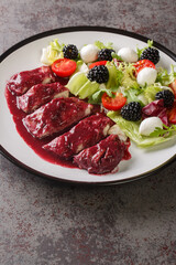 Fried chicken fillet with blackberry sauce served with vegetable salad with mozzarella cheese close-up in a plate on the table. Vertical