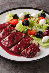 Blackberry Chicken with sweet, tart and savory blackberry butter sauce served with fresh salad closeup in the plate on the table. Vertical