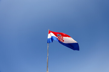 Croatian flag flying on a tower along the walled city of Dubrovnik

