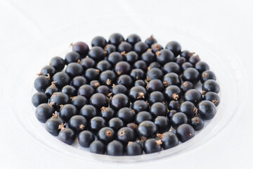 Fototapeta na wymiar Black berries on white. Blackcurrants in a transparent bowl isolated on a white background. Blackcurrant with copy space closeup. Currant organic berries harvest - healthy eating and food concept