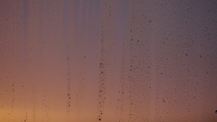 Water drops on window glass with sunset light