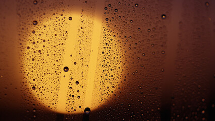 Water drops on window glass with sunset light