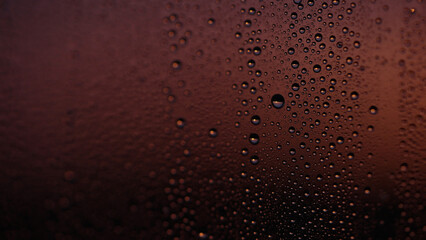 Water drops on window glass with sunset light