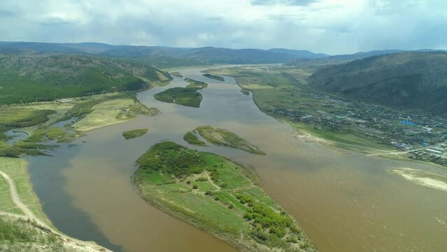 Helicopter Siberia incredible countryside spring landscape. Selenga river serpentine, riverbed flows through plain among mountains. Authentic village, railway. Green islands in water. Baikal region