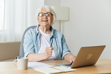 Fototapeta na wymiar Happy, successful female leader. Modern technology in educational process. Portrait of senior woman sitting at desk with laptop.