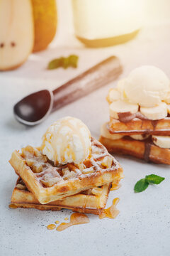 Sunlit image of waffles topped with chocolate paste, banana slices and icecream
