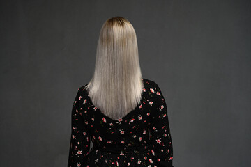 Portrait of a beautiful young blonde woman with long wavy hair, rear view