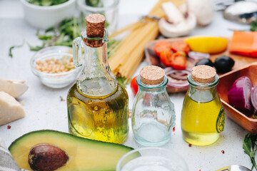 Oil bottles, avocado half and other cooking ingredients on the table.