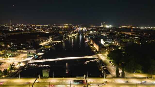 Night aerial hyperlapse shot of illuminated city. Forwards fly above water canal in central city. Copenhagen, Denmark