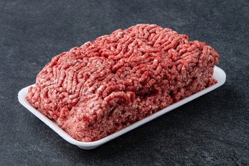 Fresh raw minced beef on backing paper over dark gray cement background