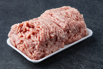 Fresh raw minced beef on backing paper over dark gray cement background