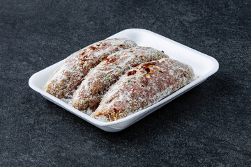Frozen Raw sausage semi-finished products lie on a stone board. The concept of cooking from semi-finished products