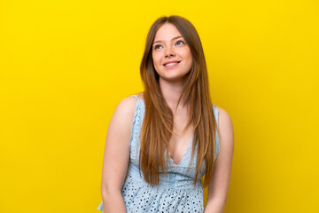 Young caucasian woman isolated on yellow background thinking an idea while looking up