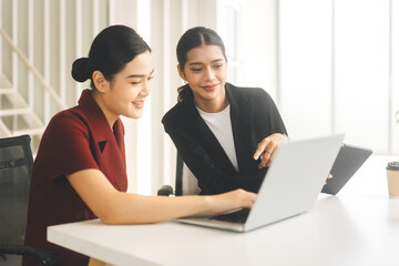Young adult woman wearing black suit teach lady intern using laptop brief for work in office