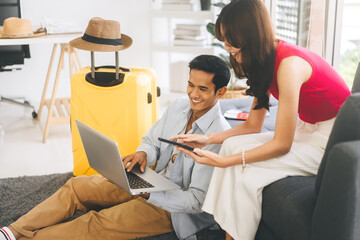 Obraz premium Young adult southeast asian couple using laptop for getting ready for holidays travel trip
