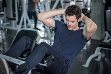 Fototapeta na wymiar Handsome man exercising doing sit up abdominal exercise in gym