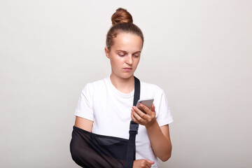 Woman with bun hairstyle wearing casual t shirt posing isolated over white background, has injured...