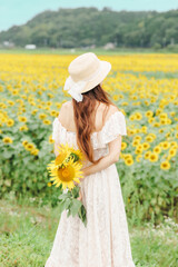 ひまわり畑に立つ女性の後ろ姿