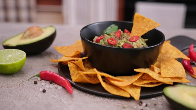 nachos chips and freshly made guacamole dip sauce in marble bowl mortar