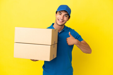 Delivery man over isolated yellow wall giving a thumbs up gesture