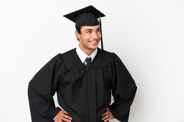 Young university graduate over isolated white background posing with arms at hip and smiling