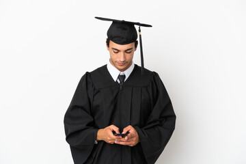 Young university graduate over isolated white background sending a message with the mobile