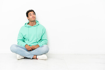 Caucasian handsome man sitting on the floor and looking up