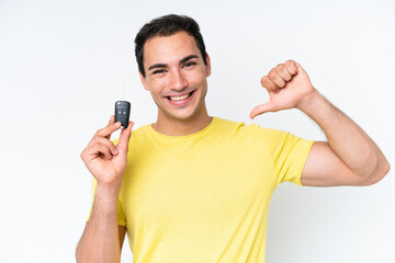 Young caucasian man holding car keys isolated on white background proud and self-satisfied