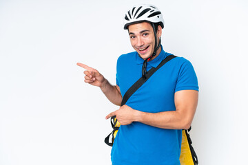 Young caucasian man with thermal backpack isolated on white background surprised and pointing side