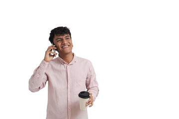 Young peruvian man smiling and talking on the phone with a cup of coffee. Isolated over white...