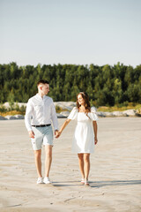 A young couple is walking along the sandy beach holding hands. on a sunny day