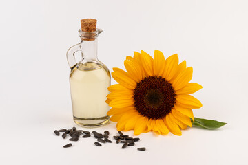 Sunflower oil in glass jug, seeds and flower isolated on white background