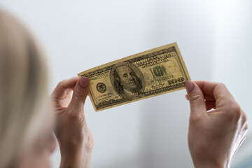 Checking counterfeit money light. 100 dollars against the window in his hand. Check for watermark...
