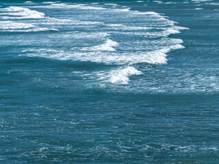 Fototapeta premium Beautiful foam on turquoise tidal waves. The surface of the water as a background. Blue ocean water