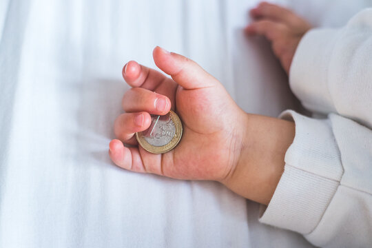 Inflation and financial security concept: Close up of newborn baby holding a euro coin