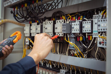 Electrical engineer using measuring equipment to checking electric current voltage at circuit breaker and cable wiring system , Electrical service concept .