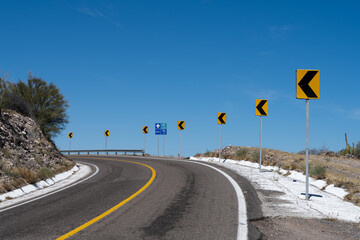  road turn to the left with road signs against blue sky