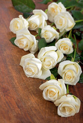 bouquet of white rose with green leaves on a wooden