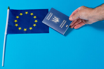 european union flag and a hand holding out a ukrainian passport to the flag, the concept of joining...
