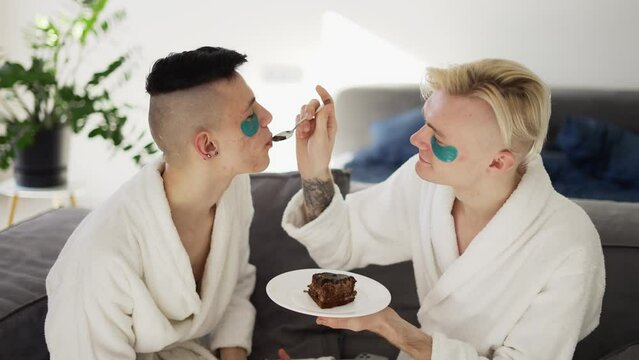 Domestic homosexual couple feeding each other with cake