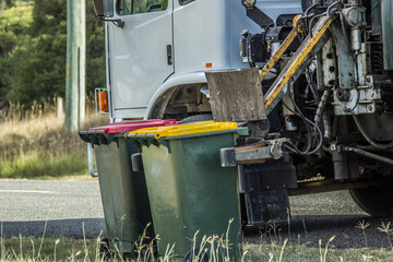 Recycling bin being collected and emptied by truck