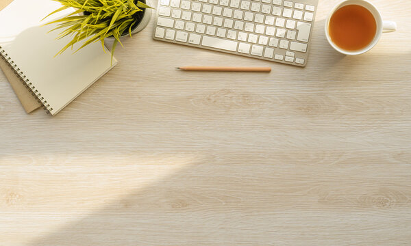 Flat lay of top view desk work table with Coffee computer notebook and pencil work space in minimal wood warm tone concept includes copyspace for add text or graphic
