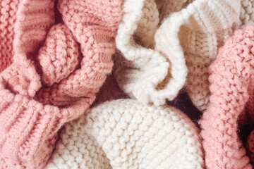 Fototapeta na wymiar The texture of knitted things close-up. Soft knitted warm clothes of white and pink color.