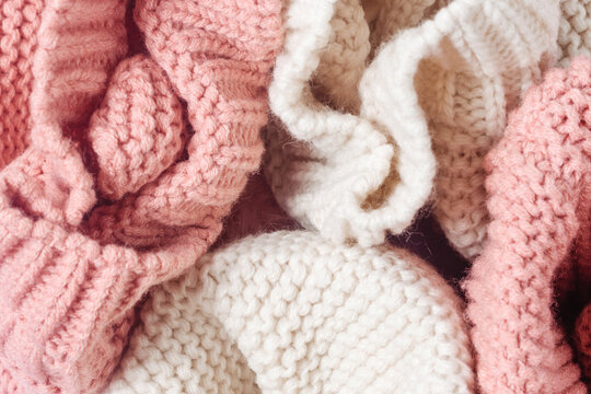 The texture of knitted things close-up. Soft knitted warm clothes of white and pink color.