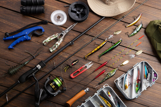 Fishing tackle - fishing spinning rod, hooks and lures on wooden background. Active hobby recreation concept.