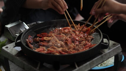 some delicious grilled meats and sausages with added onions and barbecue sauce ready to eat using chopsticks with friends and family