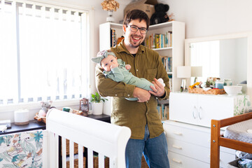 Happy young Aussie dad holding three month old baby daughter in home