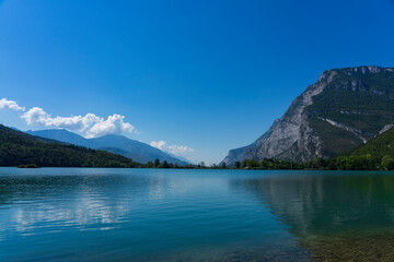 Toblino lake, Trentino Alto Adige. Marvelous large mountain lake in the hills of northern Italy. Flat water surface and clear blue sky. Popular swimming lake.